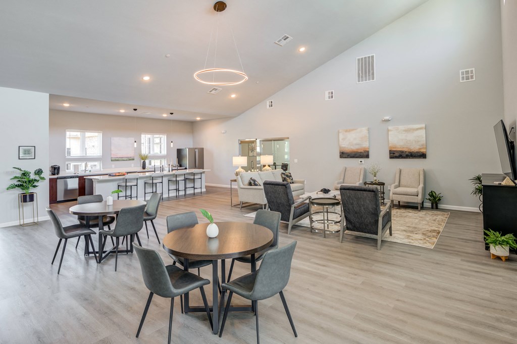 a living room and dining room with tables and chairs and a kitchen