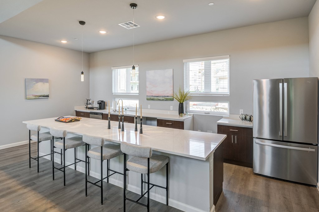an open kitchen with a large island and stainless steel refrigerator