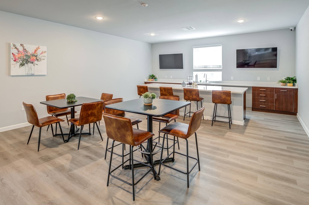 a dining area with a table and chairs and a kitchen with a television