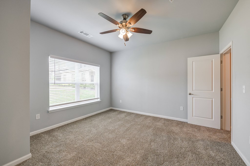 an empty room with a ceiling fan and a window