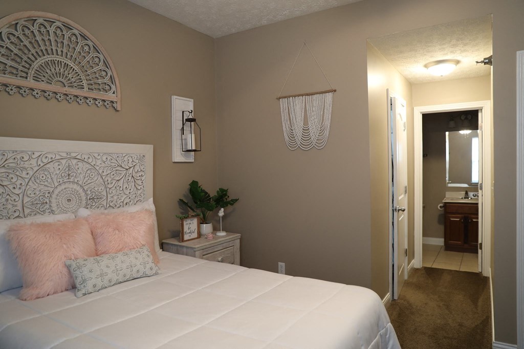 a bedroom with a large white bed and a door to a bathroom