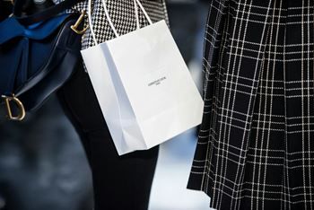 two women are holding white bags on their legs