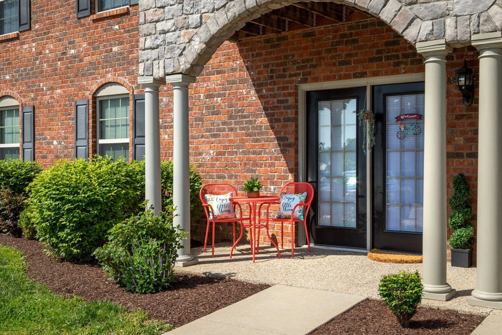 a patio with chairs and a table outside of a brick building