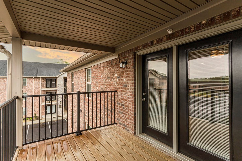 the deck of a home with a balcony and a brick building