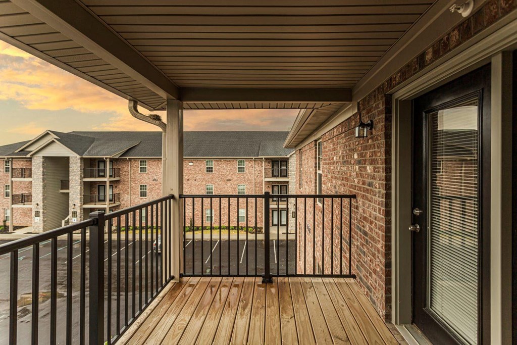 a balcony with a view of a brick building and a wooden deck