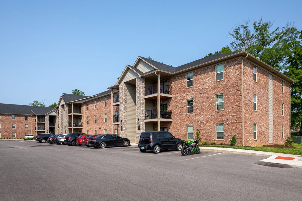 a large brick apartment building with cars parked in a parking lot