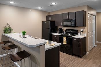 modern kitchen with black appliances and white countertops in an apartment