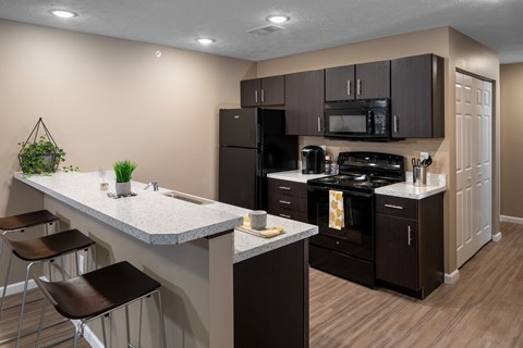 modern kitchen with black appliances and white countertops in an apartment