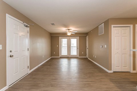 an empty living room with white doors and a ceiling fan