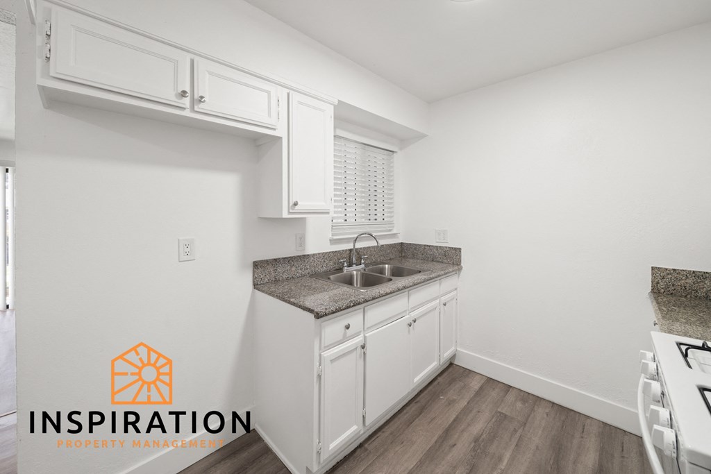 a kitchen with white cabinets and granite counter tops and a sink