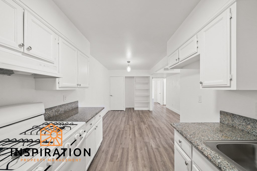 a white kitchen with granite counter tops and white cabinets