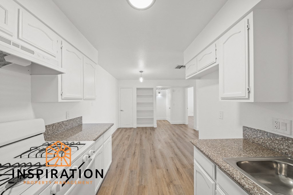 the kitchen and living room of an apartment with white cabinets and granite counter tops