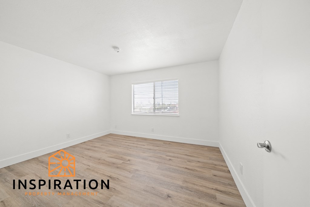 the spacious living room with wood flooring and white walls