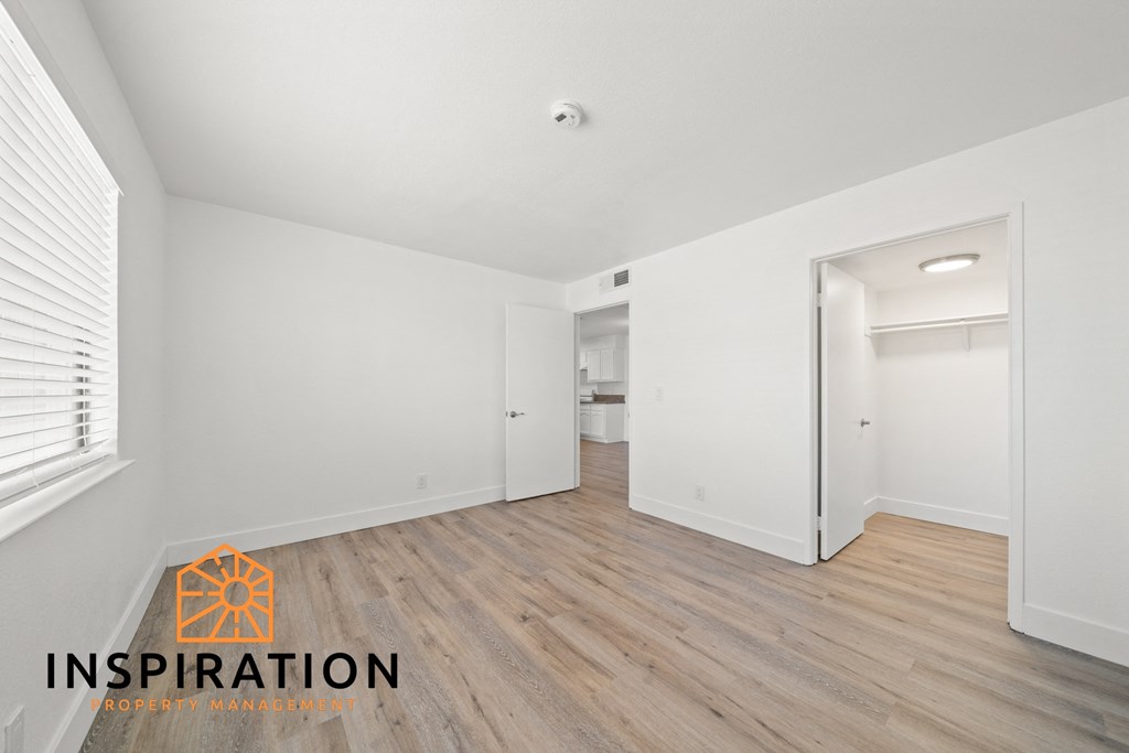 the living room of an apartment with white walls and wood floors