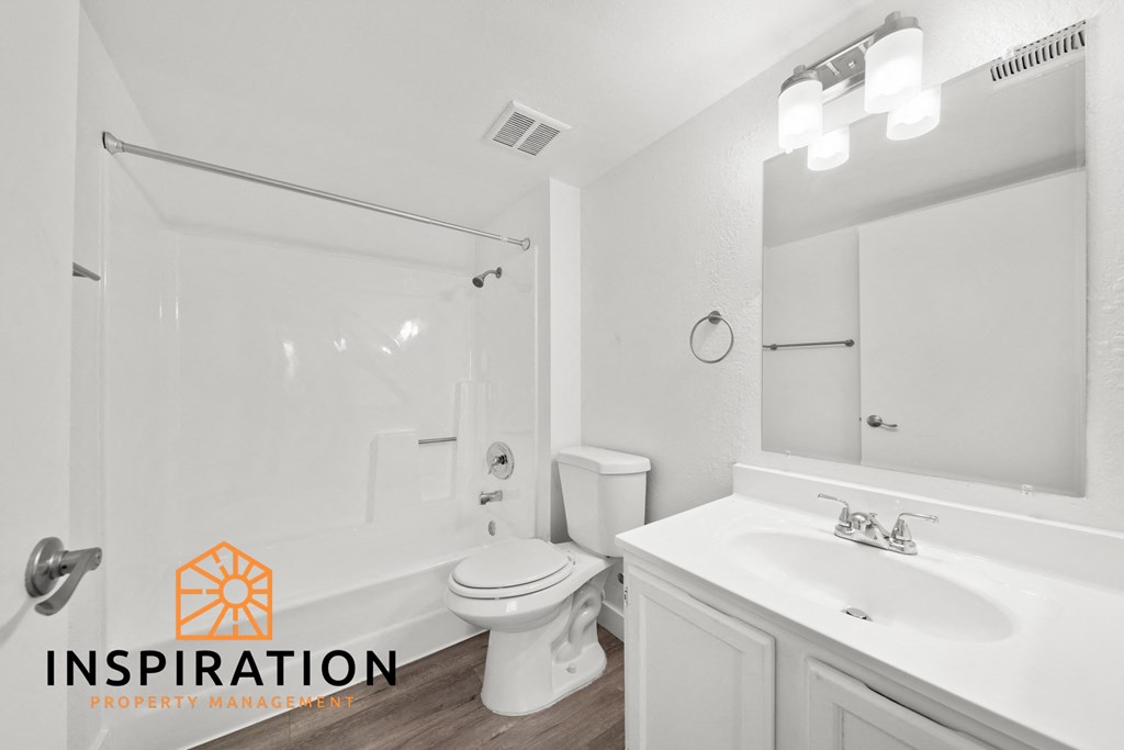 a white bathroom with a white sink and toilet and a shower