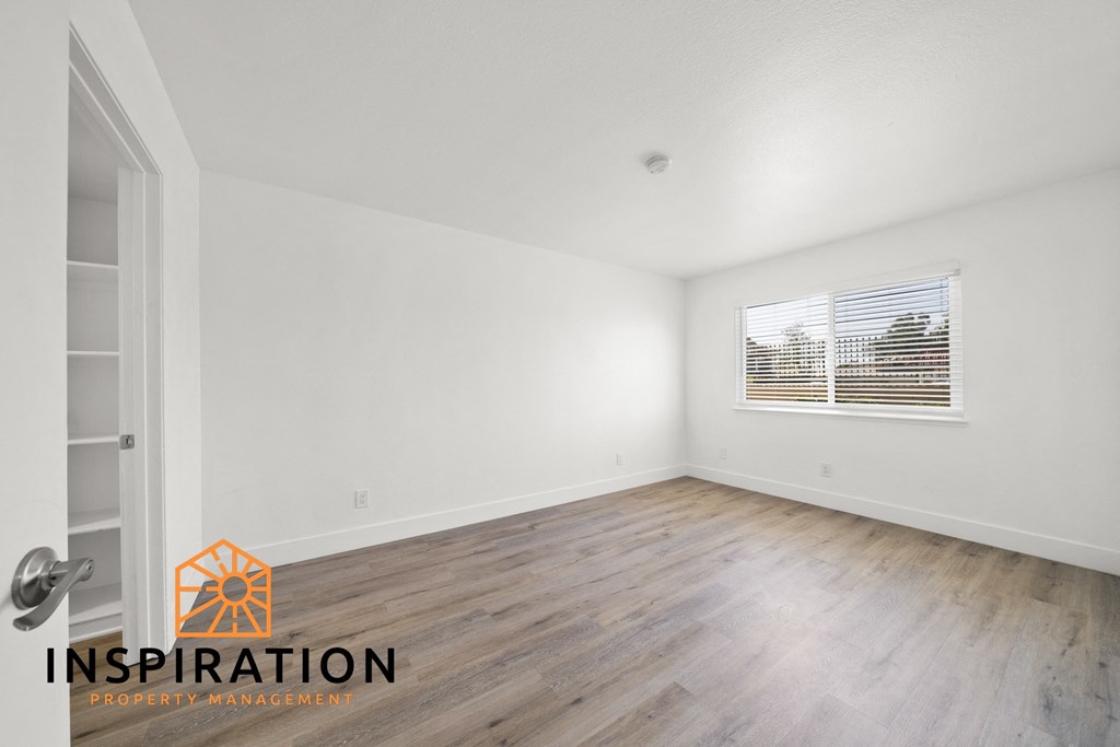 the living room of an apartment with white walls and wood floors