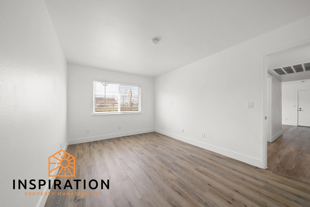 the spacious living room with wood flooring and white walls