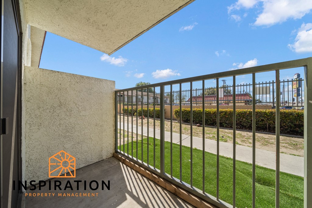a balcony with a metal fence overlooking a garden