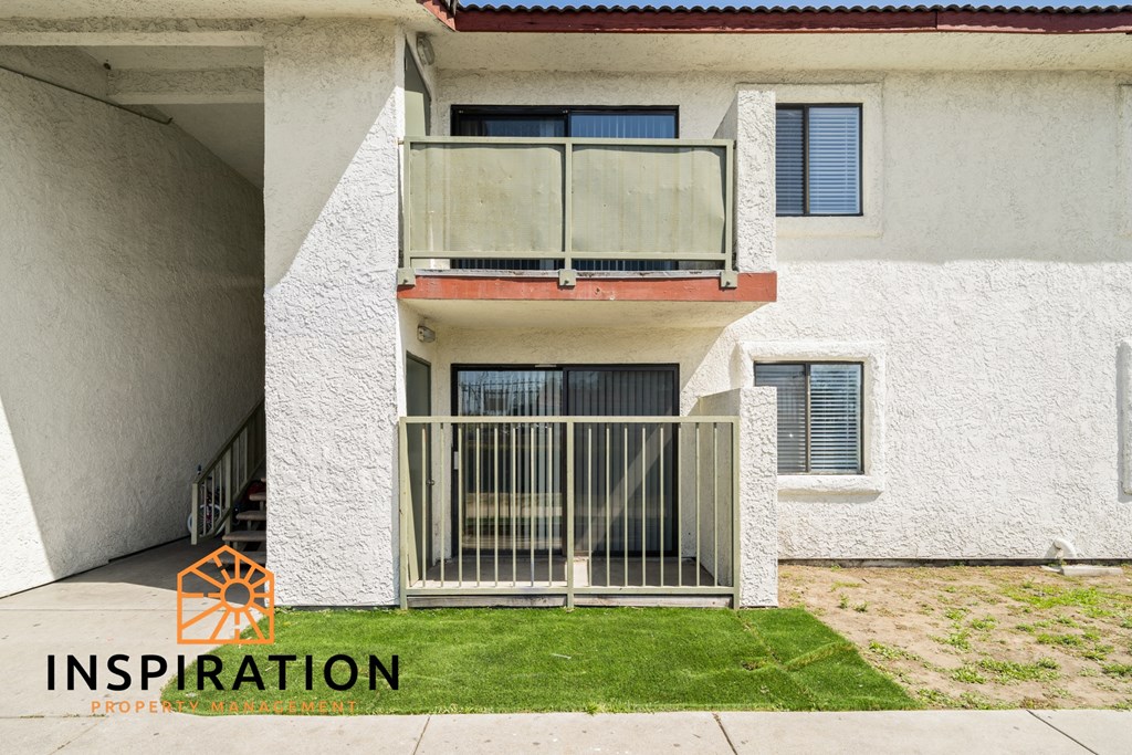 a white apartment building with a balcony and a gate