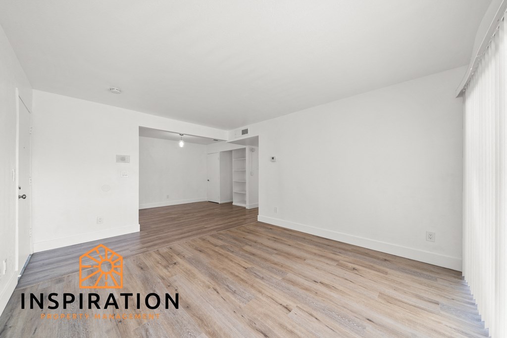 the living room and dining room with wood floors and white walls