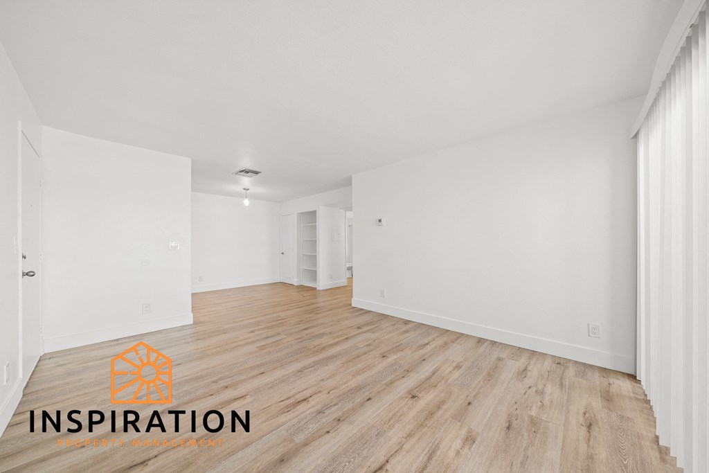 the living room and dining room with wood floors and white walls