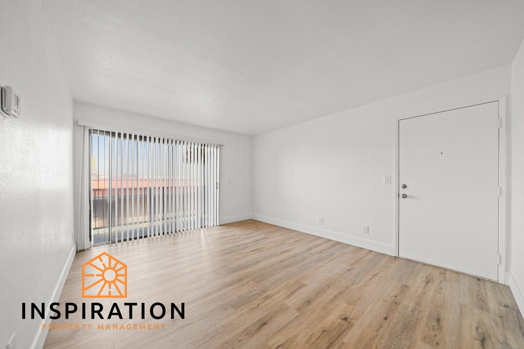 the living room of an apartment with wood flooring and a large window