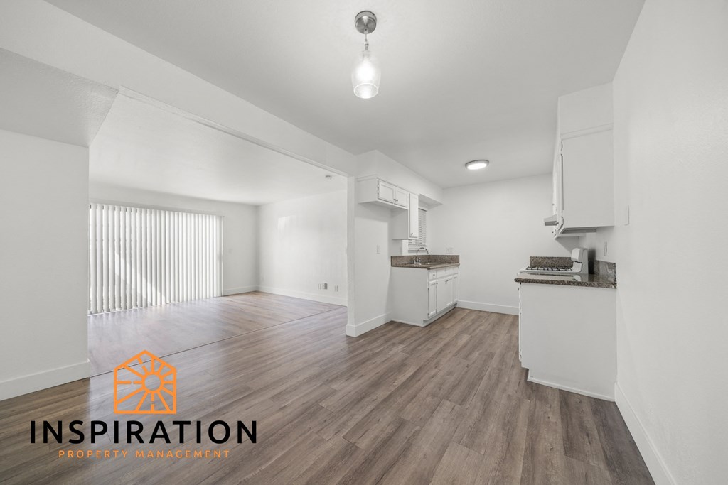 the living room and kitchen of a new home with white walls and wood flooring