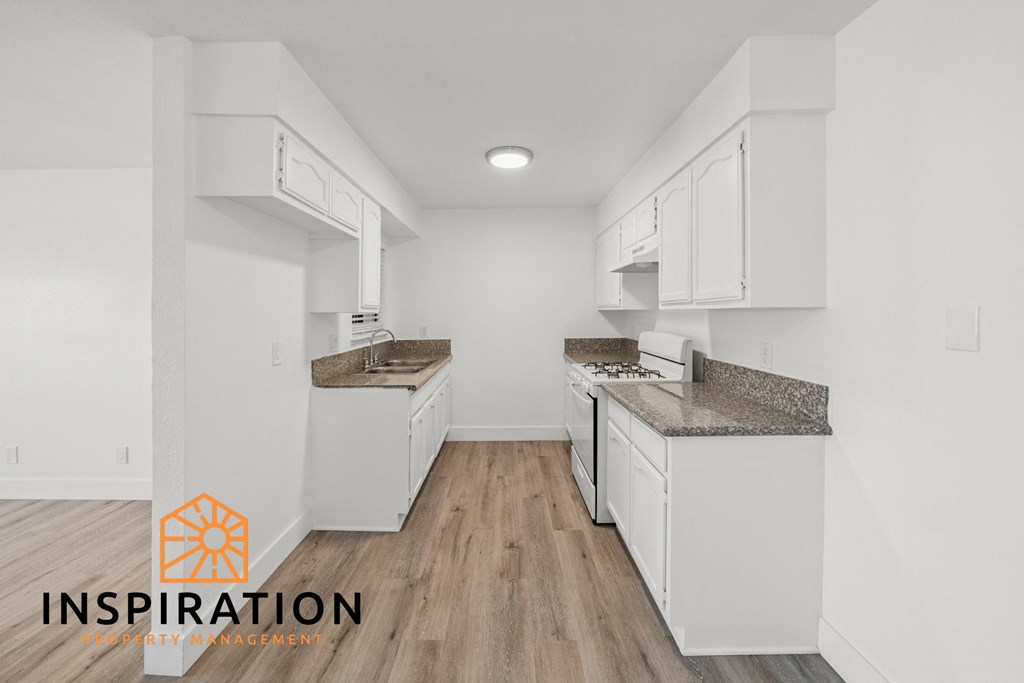 a kitchen with white cabinets and white appliances and wood floors