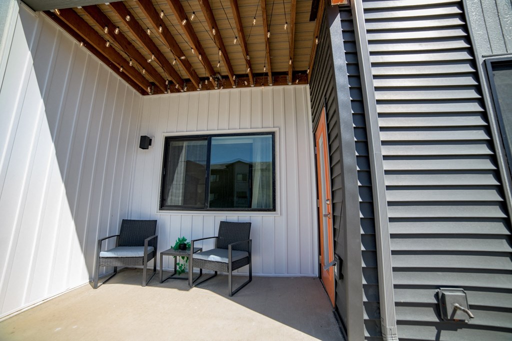 a patio with two chairs and a table under a window
