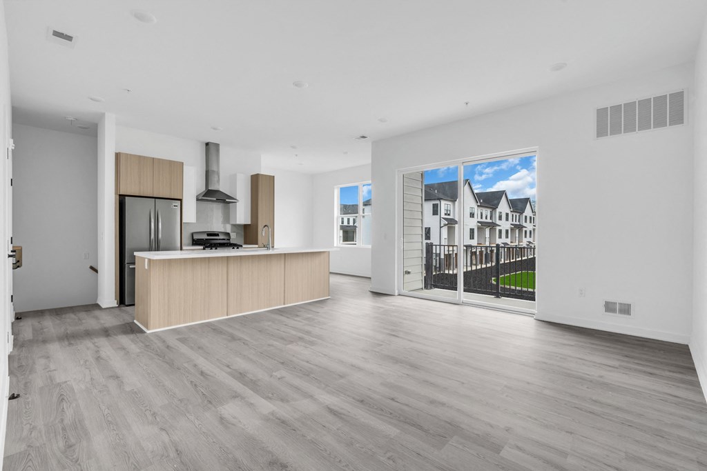 a living room with a large window and a kitchen with a counter  at The Franklin Marlboro Apartments, Marlboro, NJ