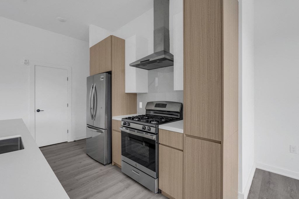 A modern kitchen with a stainless steel refrigerator, oven, and range hood at The Franklin Marlboro Apartments, Marlboro