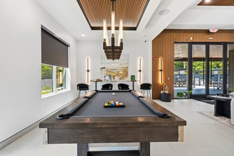 A pool table is in the middle of a room with a wooden ceiling.