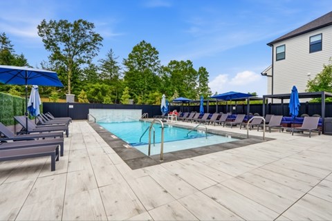 A pool surrounded by lounge chairs and umbrellas.