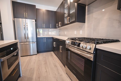 A modern kitchen with black cabinets and stainless steel appliances.at The Franklin at Westfield, Westfield, 07090
