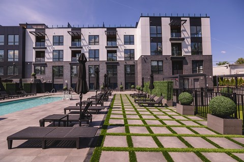A modern building with a pool and lounge chairs.at The Franklin at Westfield, New Jersey