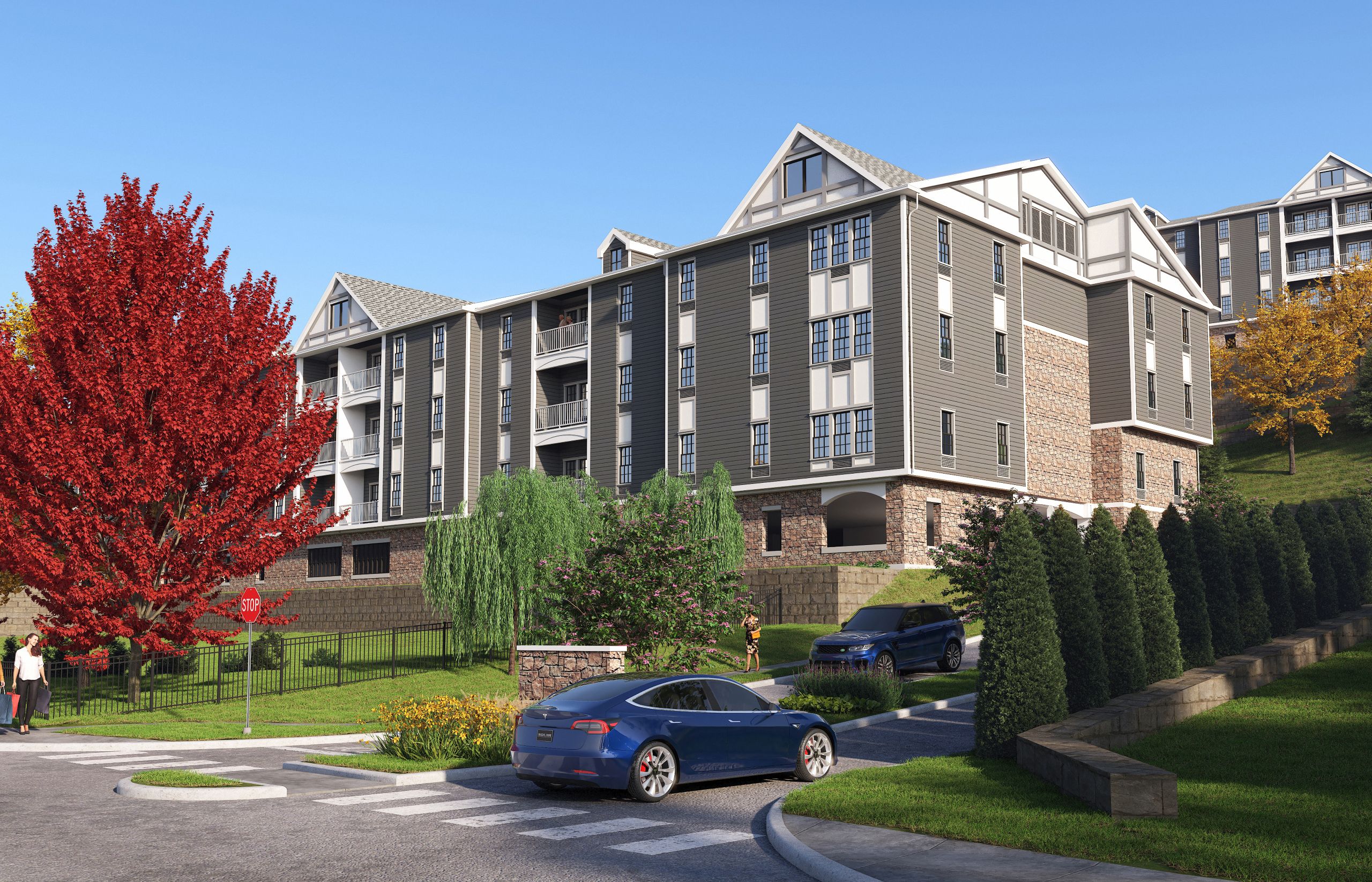 A blue car is parked on the side of a road in front of a large apartment building.