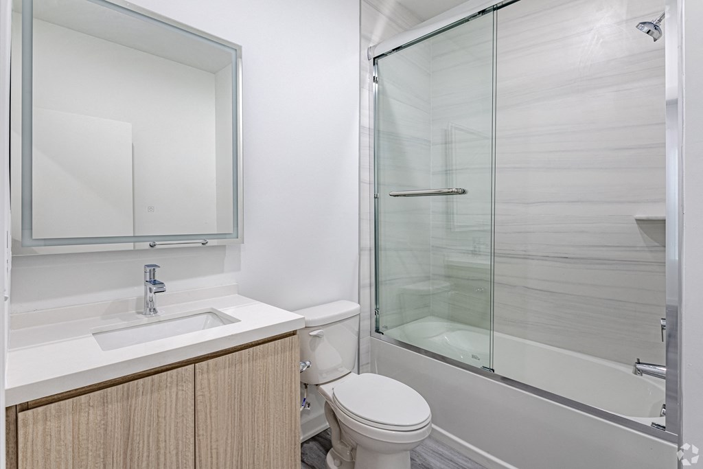 A white bathroom with a toilet, sink, and shower. at The Franklin at Marlboro, New Jersey, 07746
