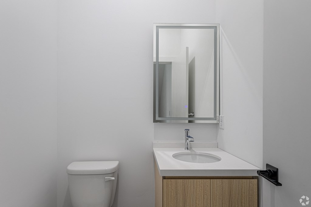 A bathroom with a toilet, sink and mirror. at The Franklin at Marlboro, Marlboro, 07746