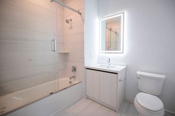 a white bathroom with a shower toilet and sink at The Franklin at Westfield, Westfield, 07090