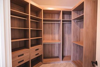 a walk in closet with wooden shelves and drawers