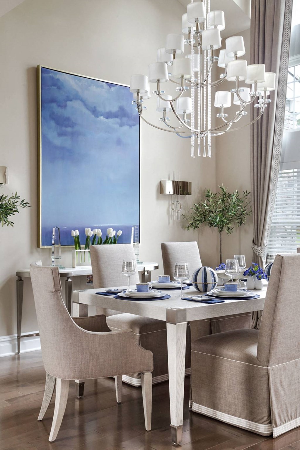 a dining room with a table and chairs and a large painting on the wall