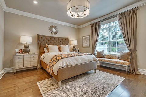 A bedroom with a large bed and a bench by the window.
