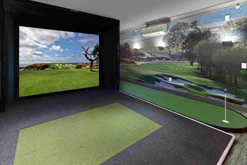 a room with a golf simulator and a large screen on the wall