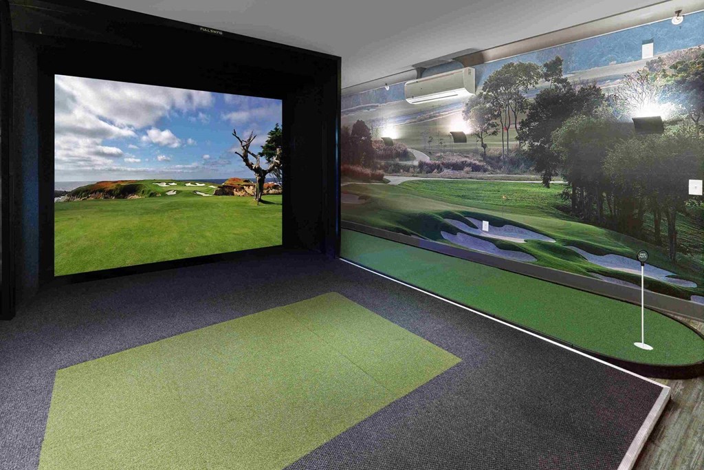 a room with a golf simulator and a large screen on the wall