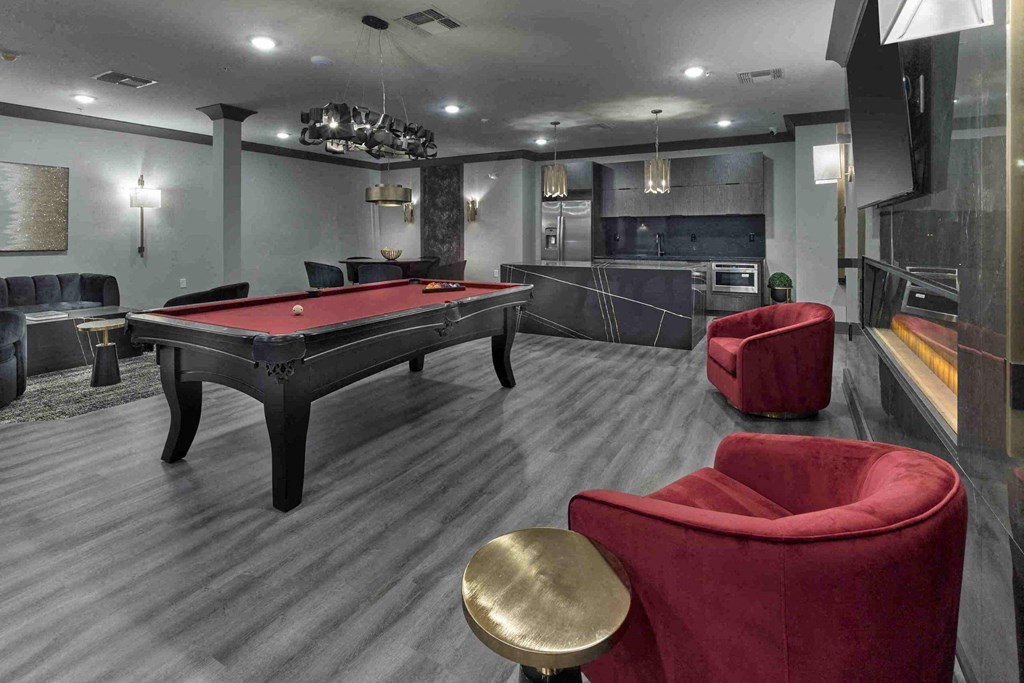 a games room with a pool table and red chairs