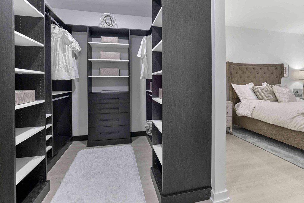 a walk in closet with a bed and a dresser
