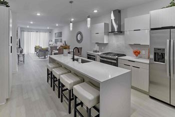 a large white kitchen with an island with white chairs
