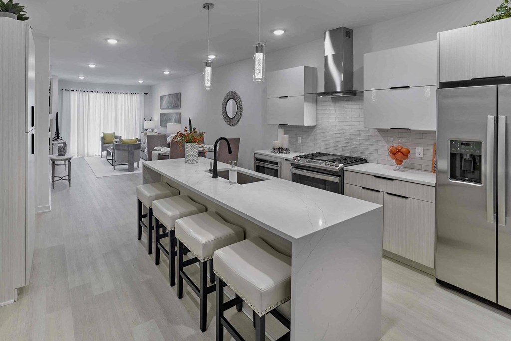 a large white kitchen with an island with white chairs