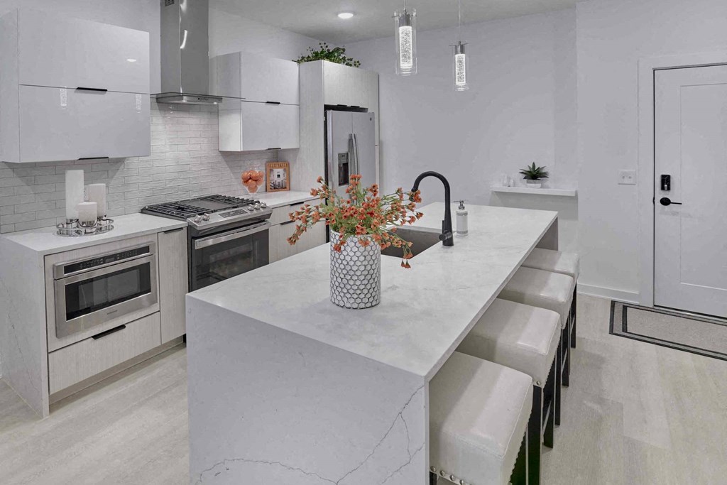 a white kitchen with a large island and white appliances
