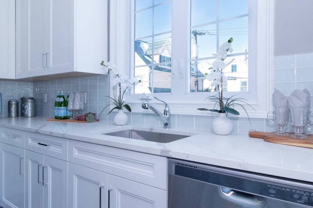 a white kitchen with a sink and a window